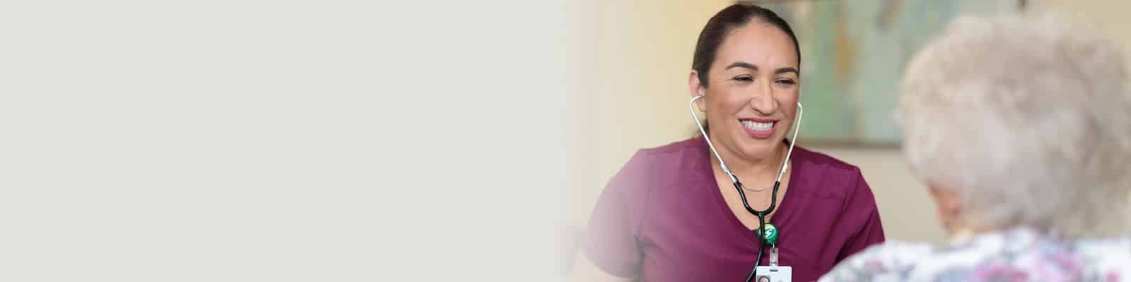 A nurse assisting an elderly woman at River Valley