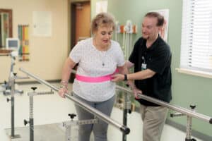 A therapist helping a woman walk at River Valley
