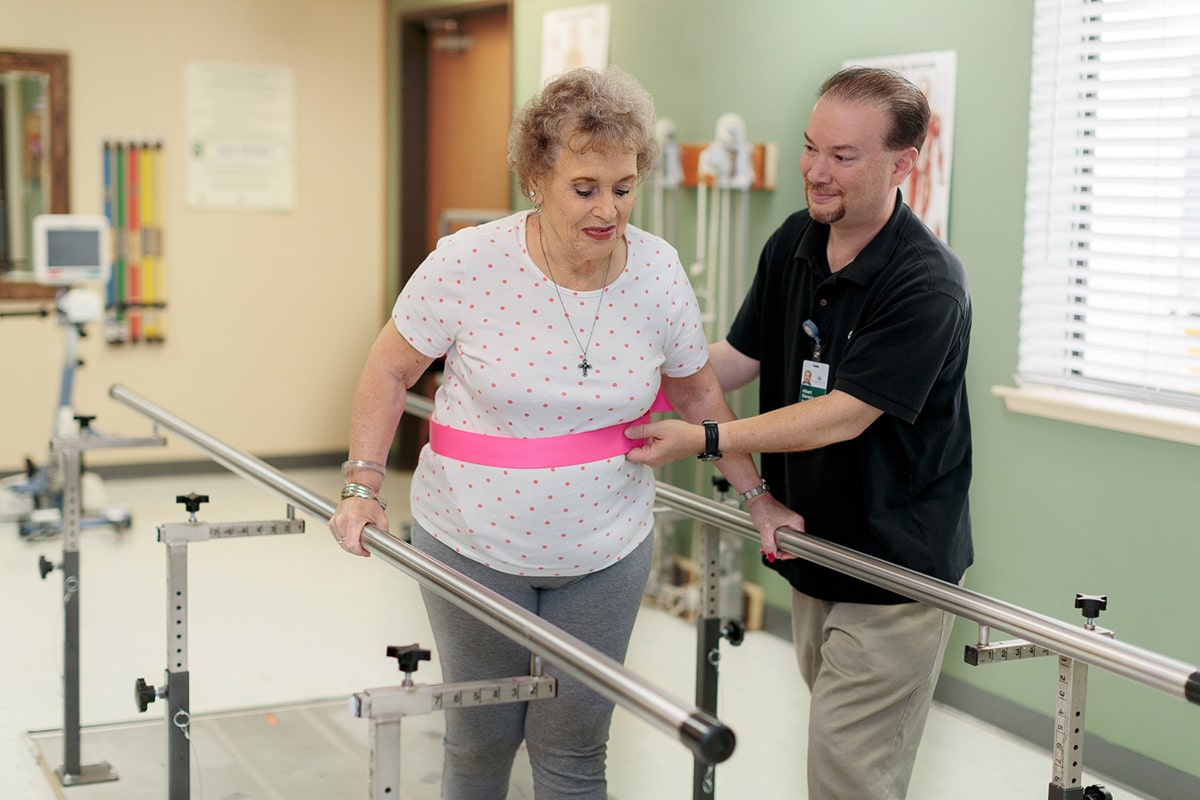 A therapist helping a woman walk at River Valley