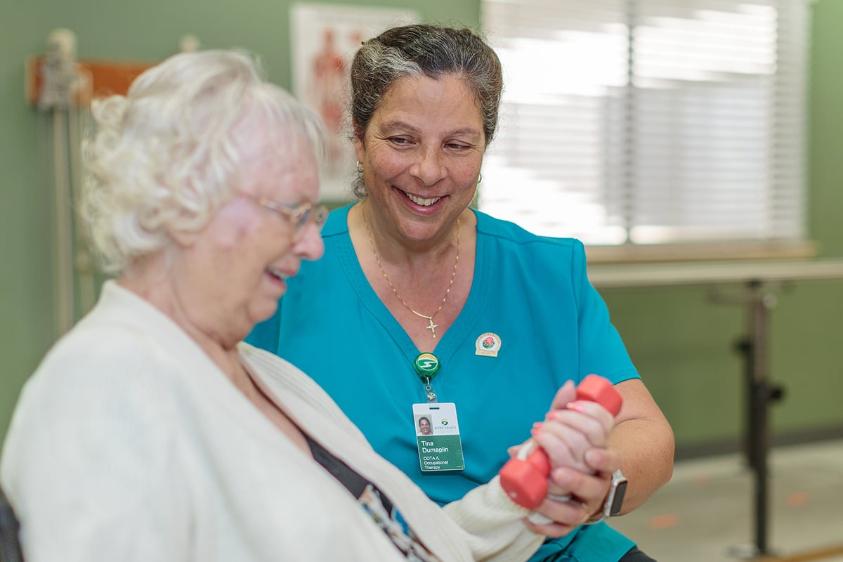 A physical therapist helping an elderly woman at River Valley